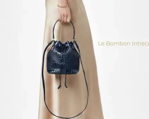 Mujer sosteniendo bolso bucket negro de piel con trenzado intrecciato y correa larga, modelo Le Bombon Intrecciato.